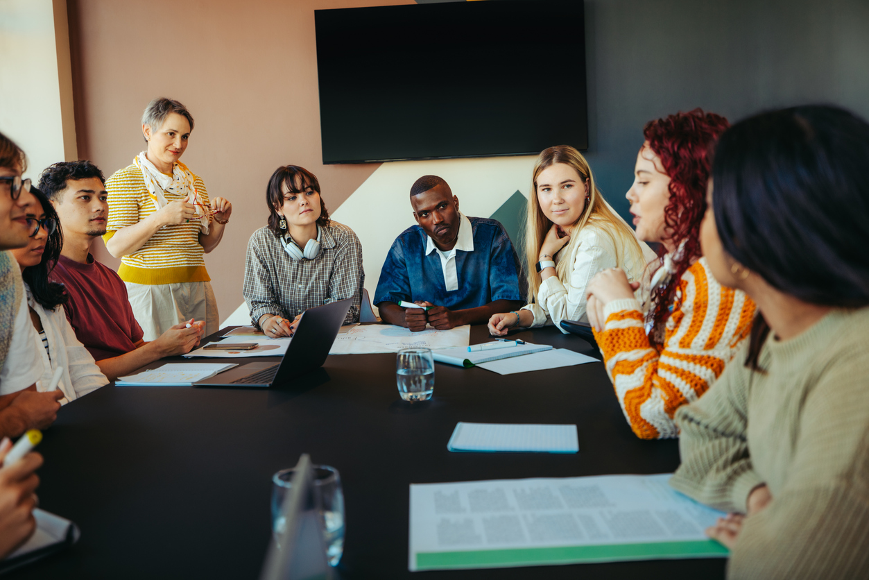 group of diverse classmates engaged in a collaborative learning discussion around a table in a modern classroom setting